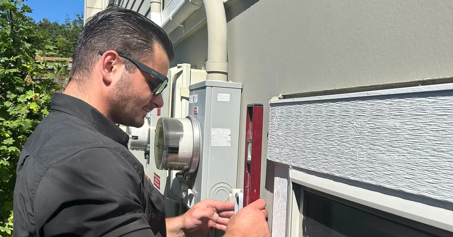 Electrician working at the service entrance on the side of a house