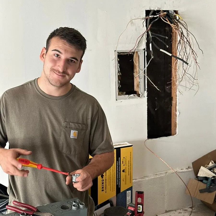 Electrician at a panel swap with the old panel removed and the branch circuit wires left waiting in the wall