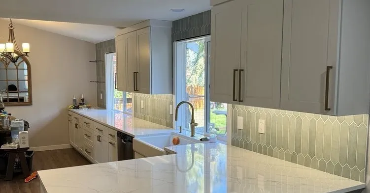 Remodeled kitchen with under-cabinet lighting and a chandelier in the room beyond