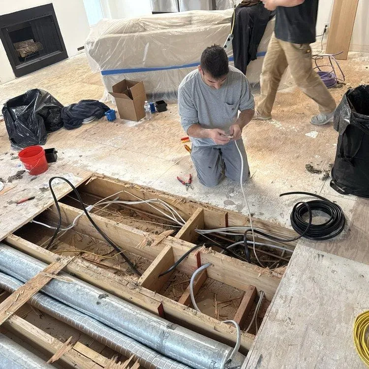 Electrician running circuits through the subfloor during a kitchen remodel