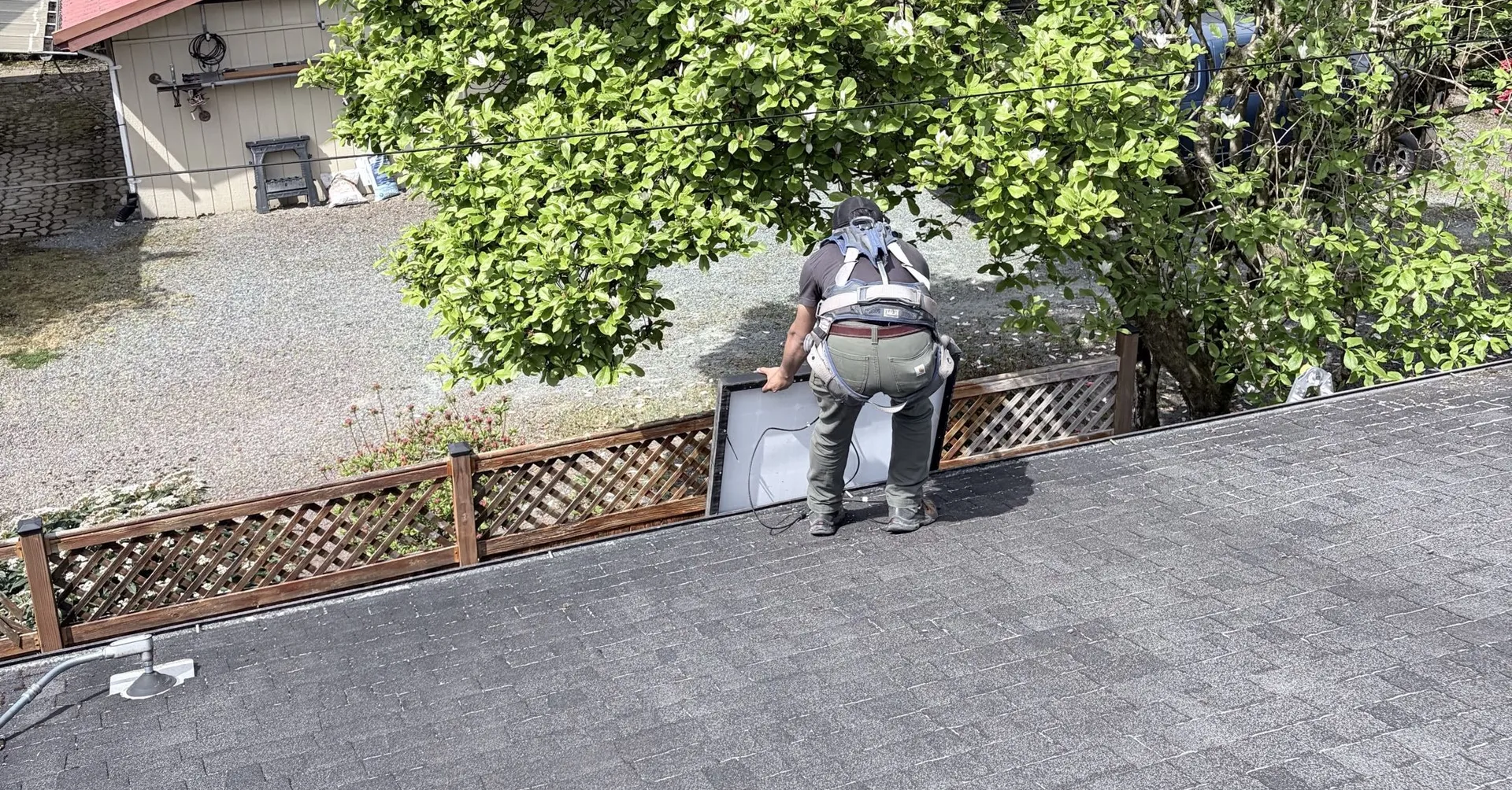 Electrician on a rooftop lifting a solar panel into place during installation