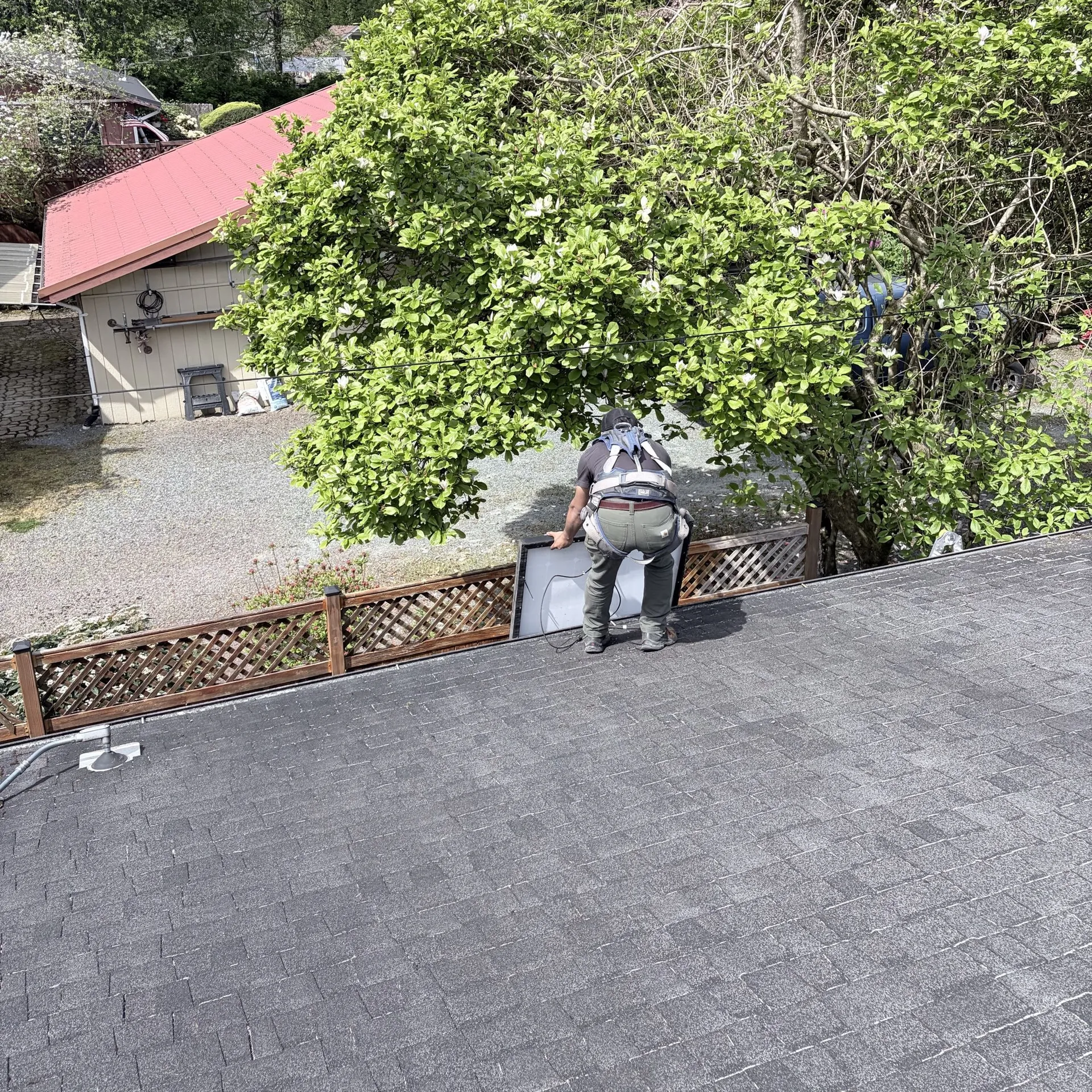 Electrician on a rooftop lifting a solar panel into place during installation
