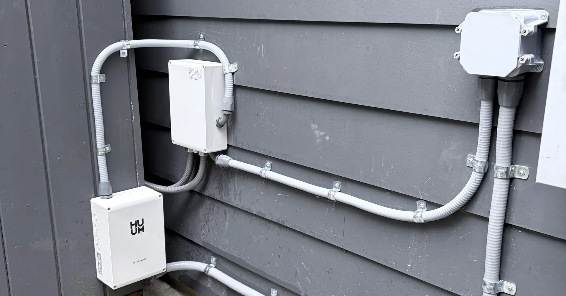 Exterior conduit runs feeding a spa emergency disconnect and HUUM controller on the side of the house