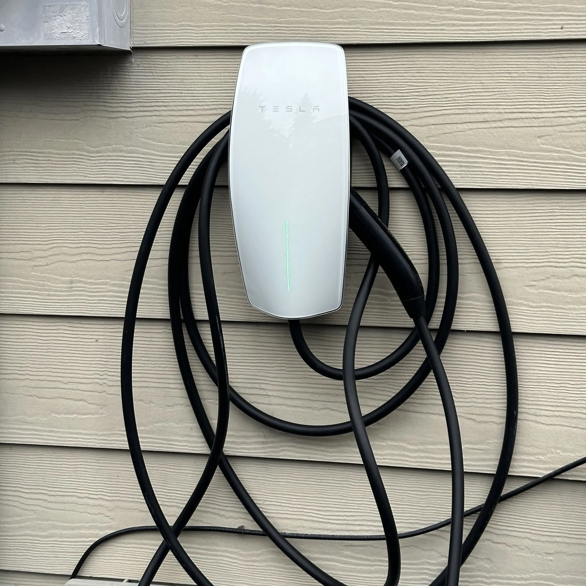Tesla Wall Connector mounted on the exterior wall of a home