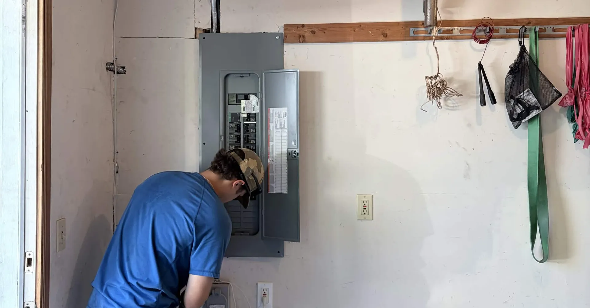 Electrician fitting a generator interlock kit to an electrical panel