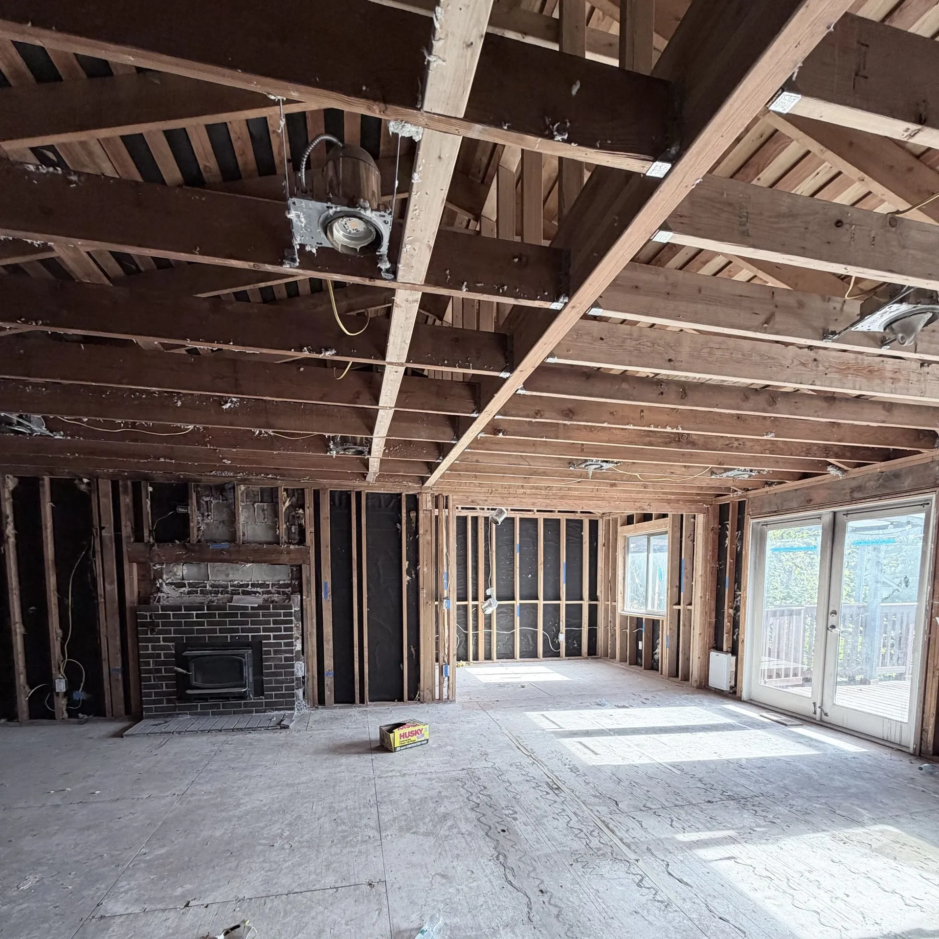 Living room stripped back to the framing around the fireplace, with the carpet, drywall and old wiring pulled out