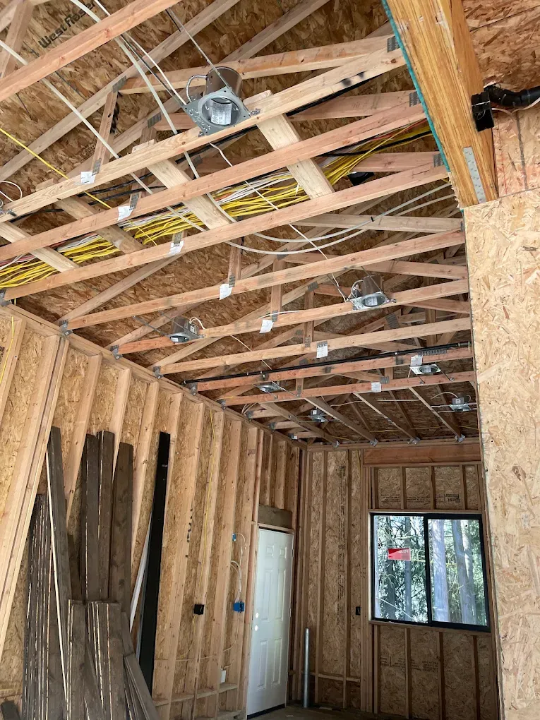Recessed can light housings laid out across ceiling framing with wiring runs before drywall
